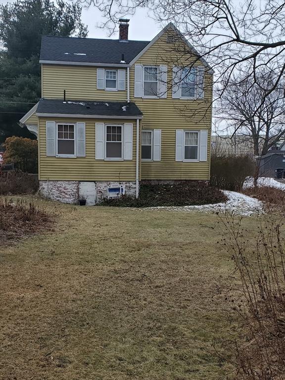 back of property with a chimney and a yard