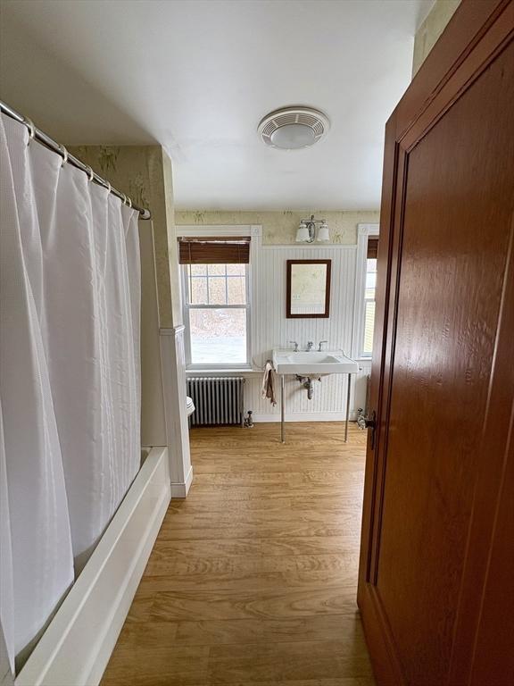 bathroom featuring shower / bath combination with curtain, toilet, radiator heating unit, and wood finished floors