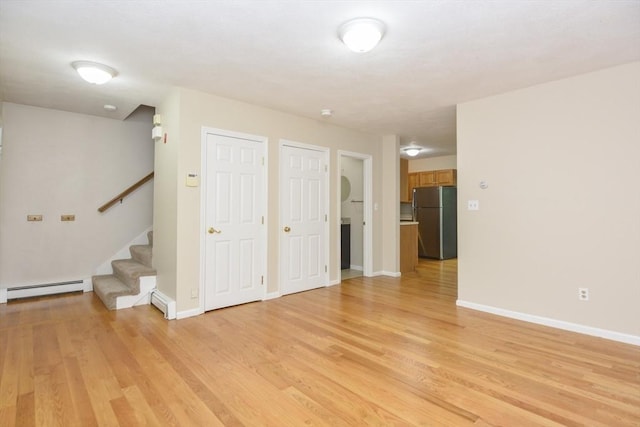 154 E Bacon St Unit B6, Plainville, MA 02762 - unfurnished living room featuring a baseboard radiator, light wood-style floors, stairs, and baseboards