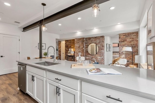 kitchen with sink, hanging light fixtures, brick wall, stainless steel dishwasher, and white cabinets