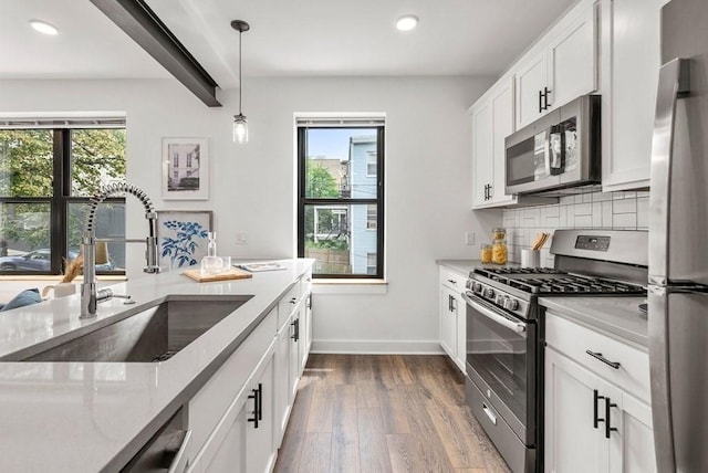 kitchen featuring pendant lighting, sink, appliances with stainless steel finishes, tasteful backsplash, and white cabinetry