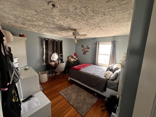 bedroom with ceiling fan, wood-type flooring, and a textured ceiling