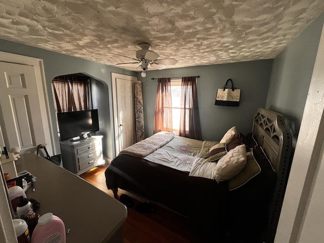 bedroom with ceiling fan, wood-type flooring, and a textured ceiling