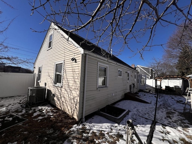 view of snow covered exterior featuring central AC and a pergola