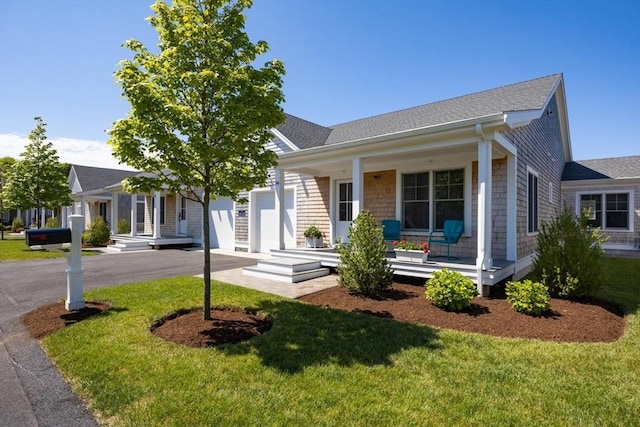 view of front facade featuring a front lawn, covered porch, and a garage