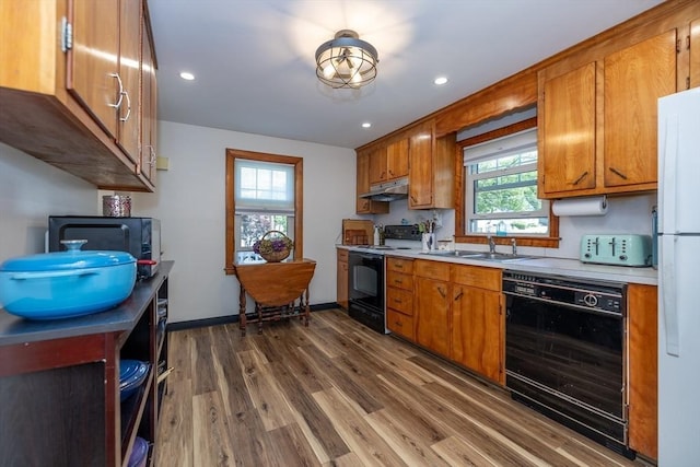 21 Alfred St, Woburn, MA 01801 - kitchen featuring black appliances, under cabinet range hood, light countertops, dark wood-style floors, and brown cabinets