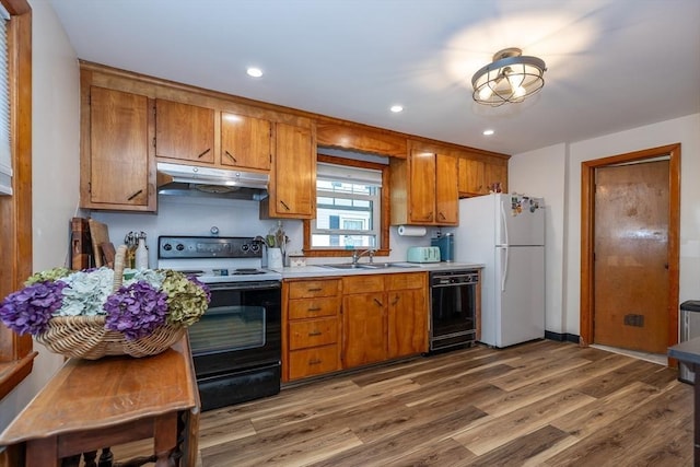 21 Alfred St, Woburn, MA 01801 - kitchen featuring under cabinet range hood, black dishwasher, range with electric cooktop, freestanding refrigerator, and brown cabinets
