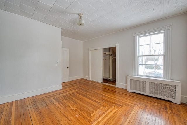 spare room with light wood-style floors, radiator, and baseboards