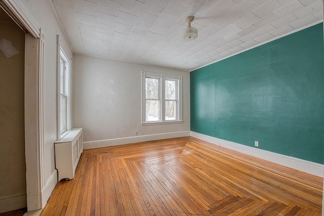 empty room with parquet floors, radiator heating unit, and baseboards