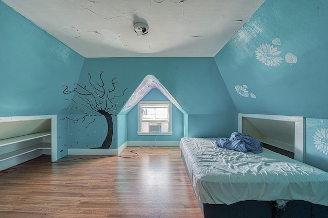 unfurnished bedroom featuring lofted ceiling, baseboards, and wood finished floors