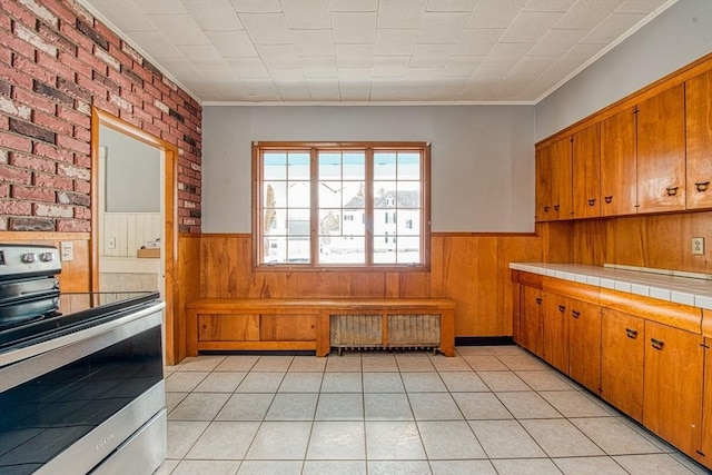 kitchen with electric stove, wainscoting, tile countertops, and radiator heating unit