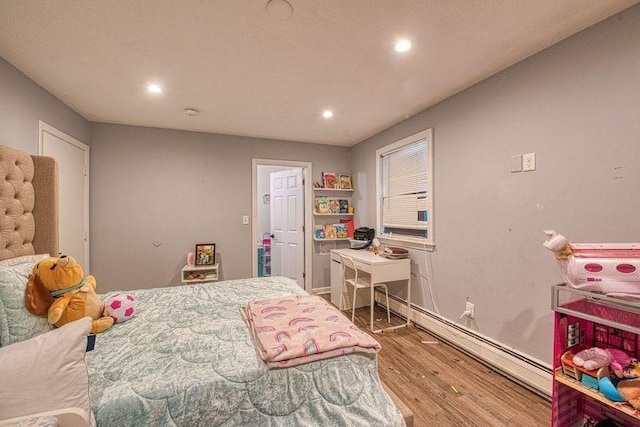 bedroom featuring a baseboard heating unit and wood-type flooring