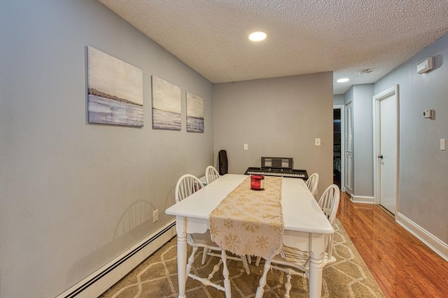 dining space featuring a baseboard heating unit, a textured ceiling, and light hardwood / wood-style floors