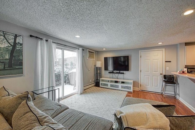 living room featuring a baseboard radiator, a wall mounted AC, a textured ceiling, and light hardwood / wood-style flooring