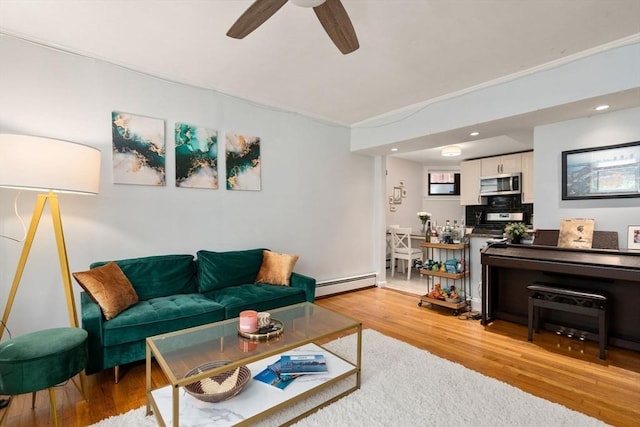 living room featuring a baseboard radiator, ceiling fan, and light wood-type flooring