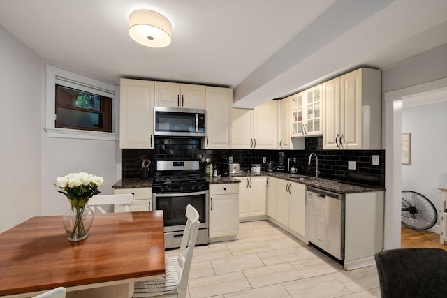 kitchen featuring dark stone countertops, backsplash, sink, and appliances with stainless steel finishes