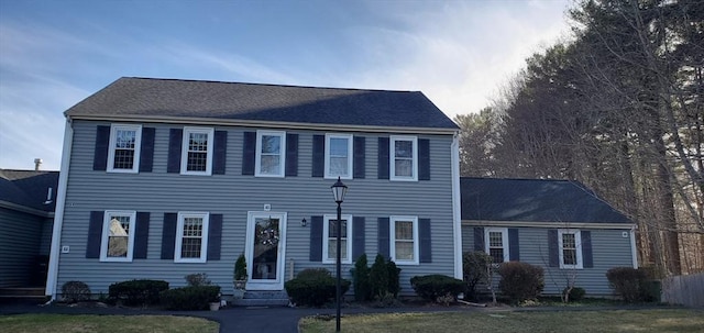 colonial-style house featuring a front lawn and entry steps