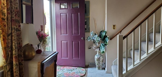 carpeted foyer entrance featuring stairs and healthy amount of natural light