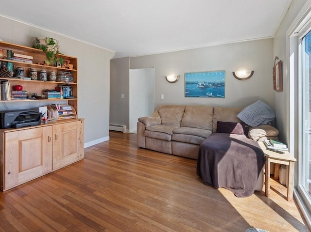 living room featuring baseboards, a baseboard radiator, ornamental molding, and wood finished floors