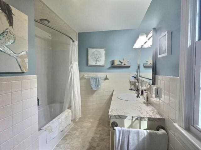bathroom with vanity, tile walls, wainscoting, and shower / bath combo