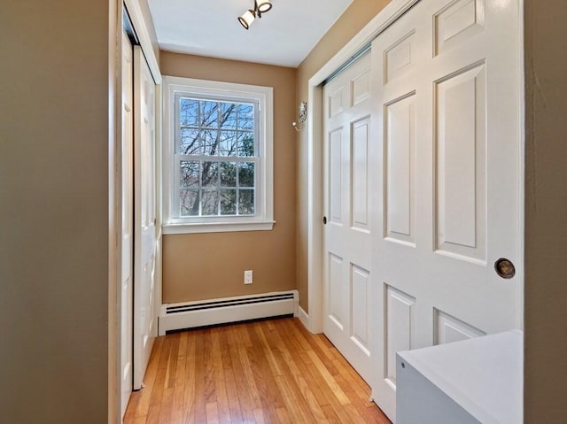 doorway to outside featuring light wood-style floors, baseboards, and baseboard heating