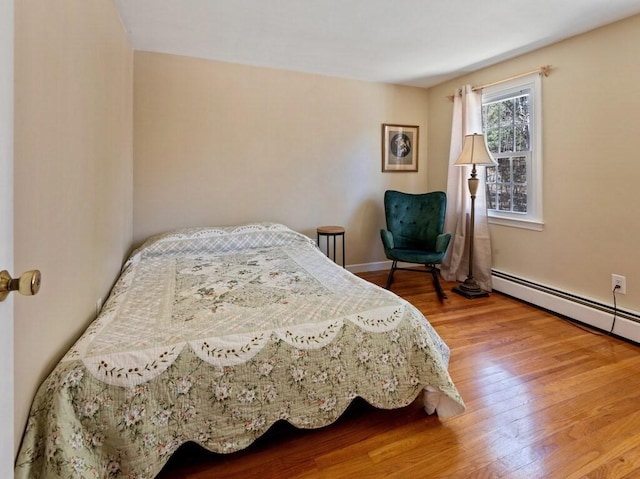 bedroom with baseboard heating, baseboards, and wood finished floors