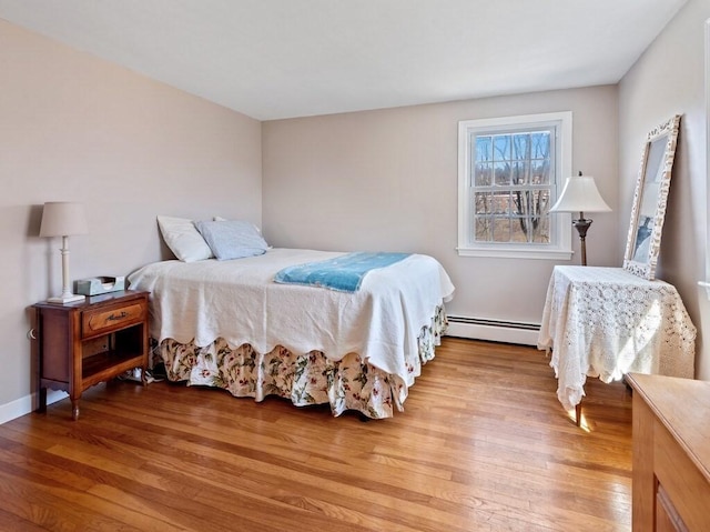 bedroom with light wood-style floors, a baseboard radiator, and baseboards