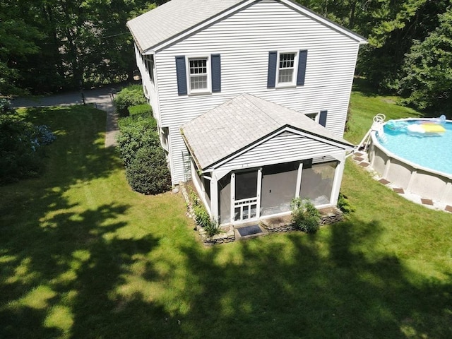 exterior space featuring a sunroom, an outdoor pool, and a front yard
