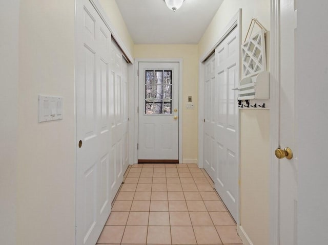 doorway featuring light tile patterned floors and baseboards