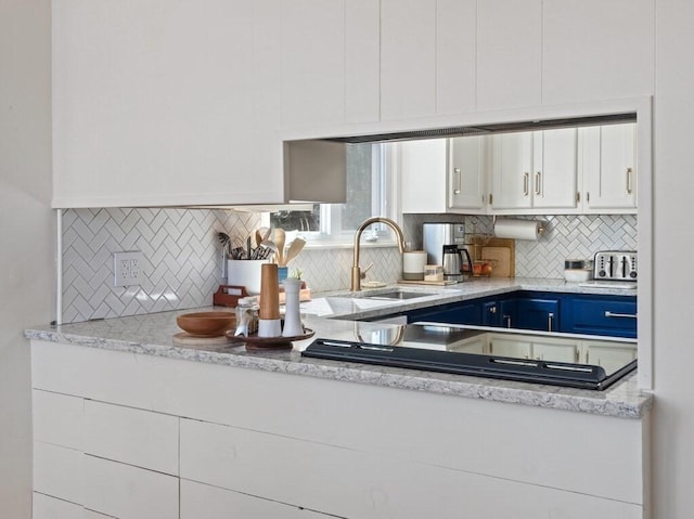 kitchen featuring a sink, decorative backsplash, blue cabinets, and white cabinetry