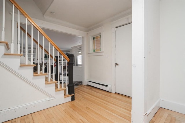 entrance foyer with wood-type flooring, baseboard heating, and ornamental molding