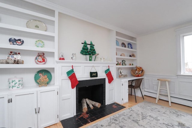 interior space with a brick fireplace, built in features, a baseboard heating unit, light hardwood / wood-style floors, and ornamental molding