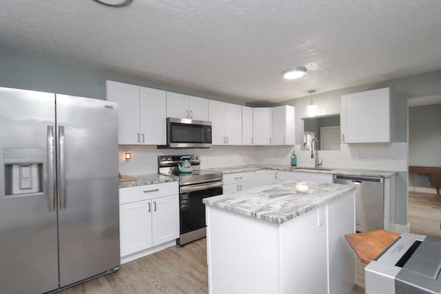 kitchen featuring stainless steel appliances, sink, light hardwood / wood-style flooring, a center island, and white cabinetry