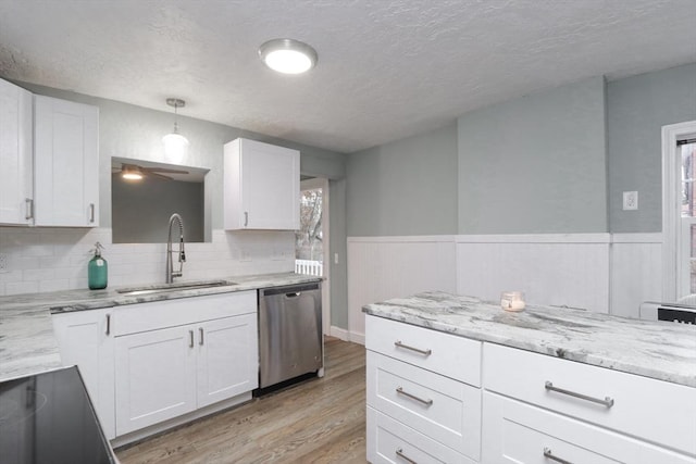 kitchen featuring pendant lighting, white cabinetry, stainless steel dishwasher, and sink