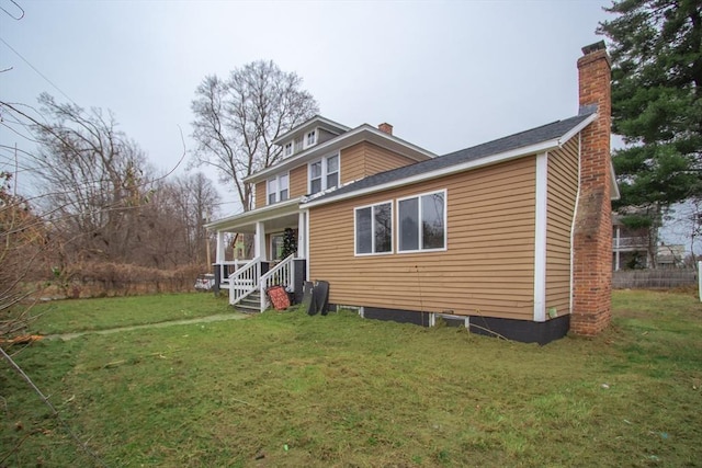 back of property with a lawn and covered porch