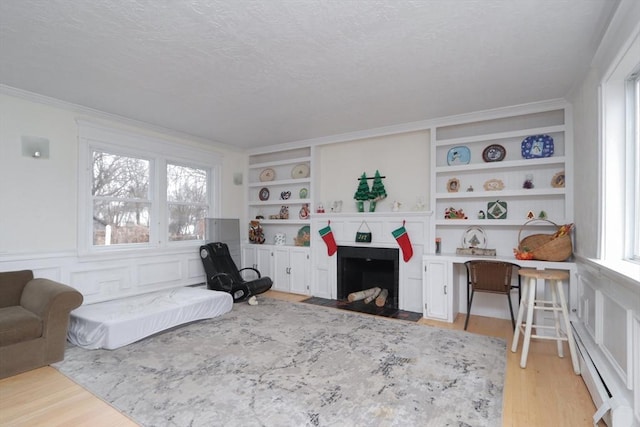 living area featuring a textured ceiling, a healthy amount of sunlight, light hardwood / wood-style flooring, and a baseboard radiator