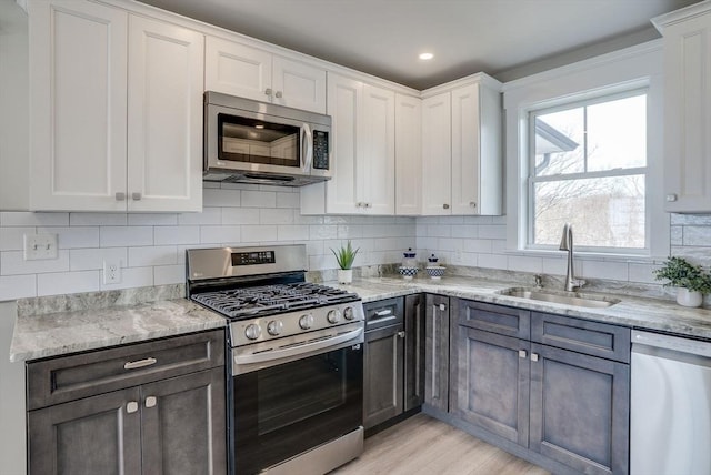 138 Flash Rd Unit 1, Nahant, MA 01908 - kitchen with stainless steel appliances, white cabinetry, light stone countertops, and decorative backsplash