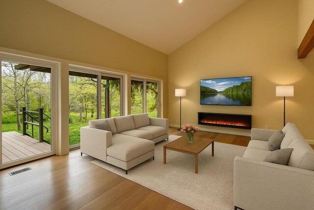 212 Charles Neck Way, West Tisbury, MA 02575 - living room with high vaulted ceiling, a warm lit fireplace, and wood finished floors