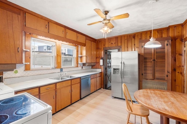 kitchen with appliances with stainless steel finishes, a sink, brown cabinets, and wooden walls
