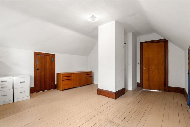 bonus room with lofted ceiling, light wood-style floors, and baseboards