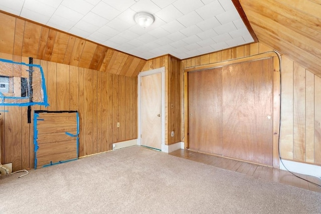 bonus room with vaulted ceiling, carpet, and wood walls