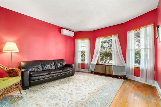 living room with radiator, an AC wall unit, wood finished floors, and baseboards