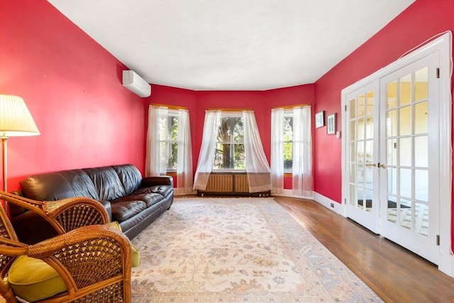 living area featuring a wall unit AC, wood finished floors, french doors, and baseboards