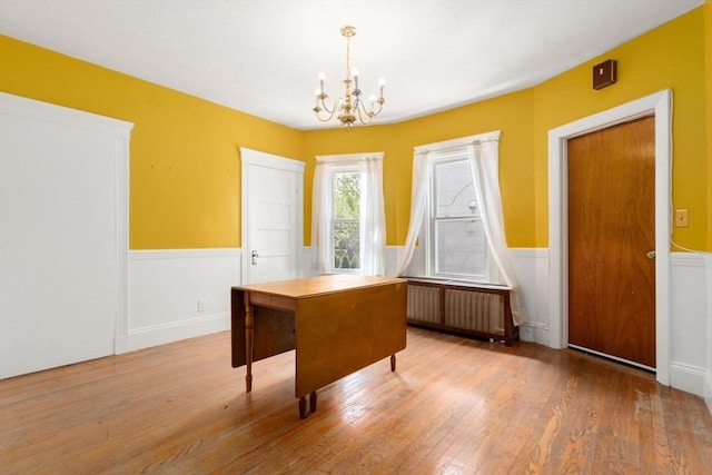 dining space with radiator, a wainscoted wall, a chandelier, and hardwood / wood-style floors