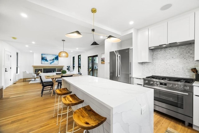 kitchen featuring pendant lighting, white cabinetry, backsplash, stainless steel appliances, and a center island