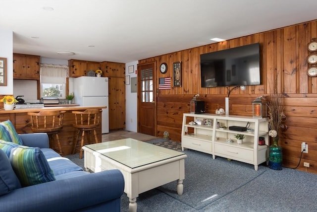 living room featuring a wealth of natural light, carpet flooring, and wood walls