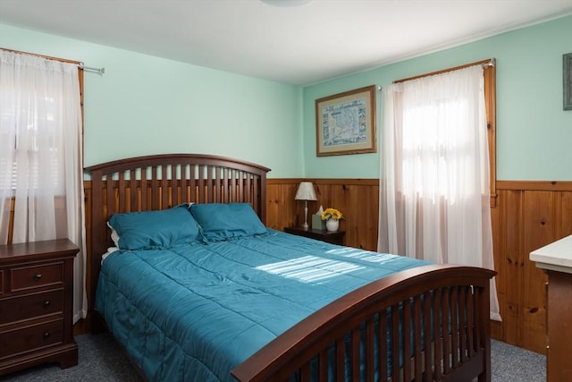 carpeted bedroom featuring a wainscoted wall and wood walls