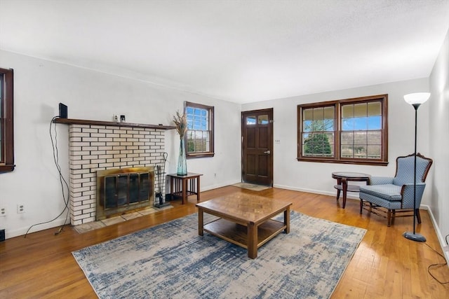 living room featuring a brick fireplace, plenty of natural light, and hardwood / wood-style flooring