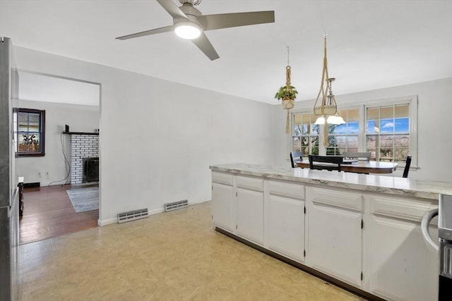 kitchen featuring white cabinetry, ceiling fan, hanging light fixtures, and light stone counters