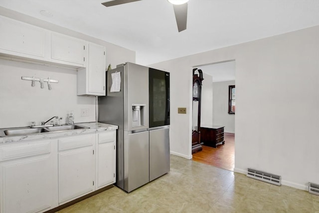 kitchen with white cabinets, stainless steel fridge, ceiling fan, and sink